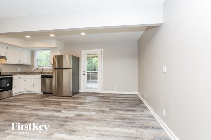 A kitchen with a refrigerator, cabinets, and a window.