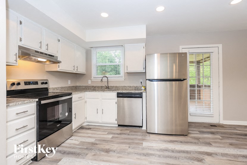 A modern kitchen with a stainless steel refrigerator, microwave, and oven.
