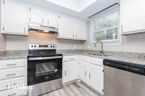 A modern kitchen with white cabinets and stainless steel appliances.