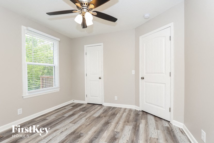 A room with a ceiling fan and two doors.