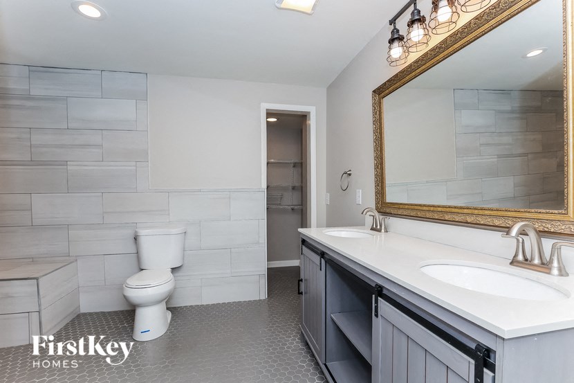 A bathroom with a toilet, sink, and mirror.