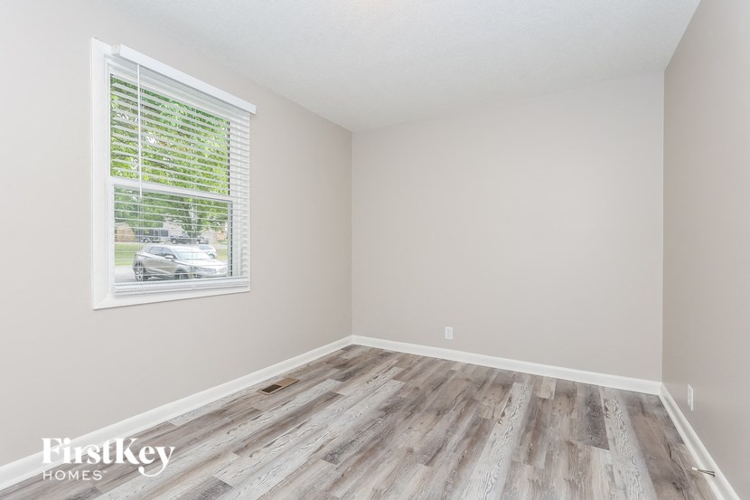 A room with wooden flooring and a window with blinds.