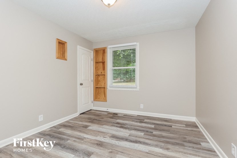 A room with a wooden floor and a window with blinds.