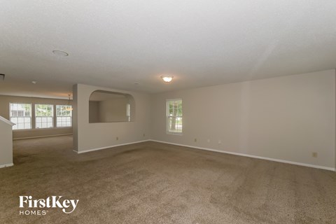 A spacious room with a carpeted floor and a large window.