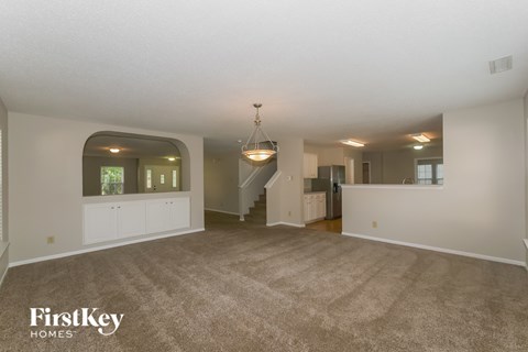 A spacious living room with a staircase and a chandelier.