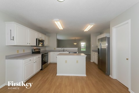 A kitchen with white cabinets and a wooden floor.