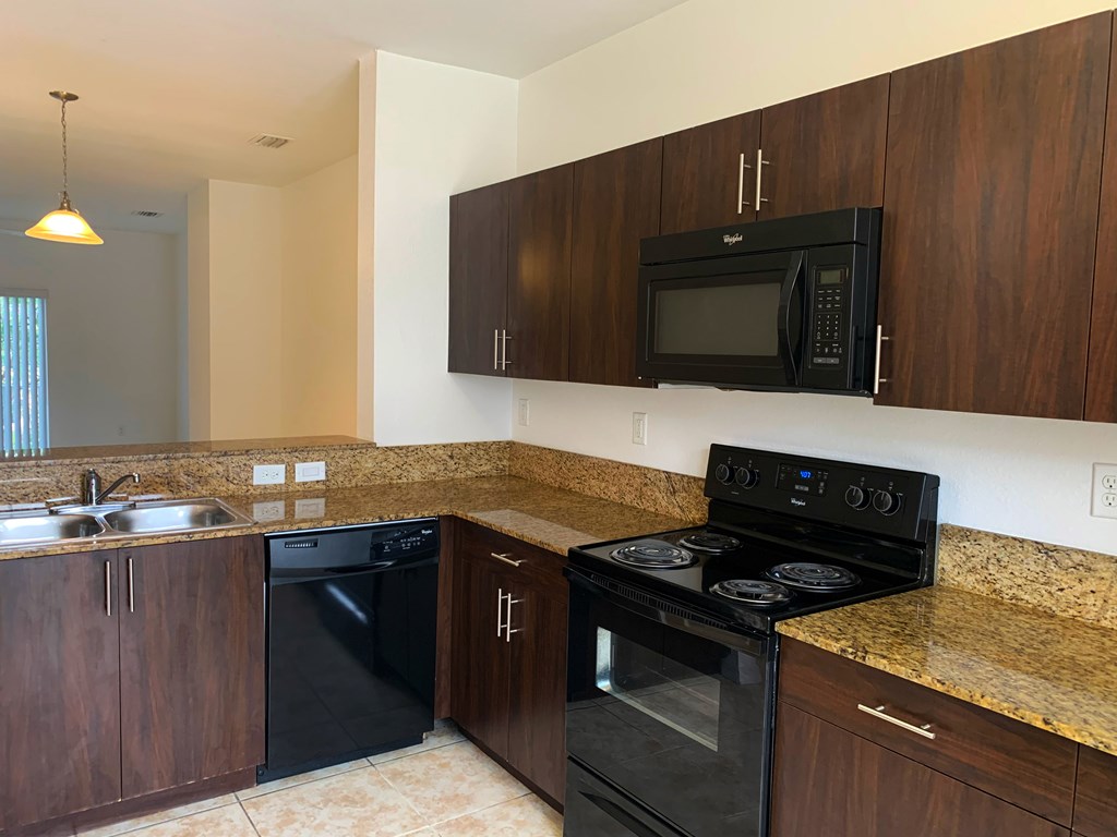 Preserve at Boynton Beach apartment home kitchen with blank appliances and dark wood cabinetry