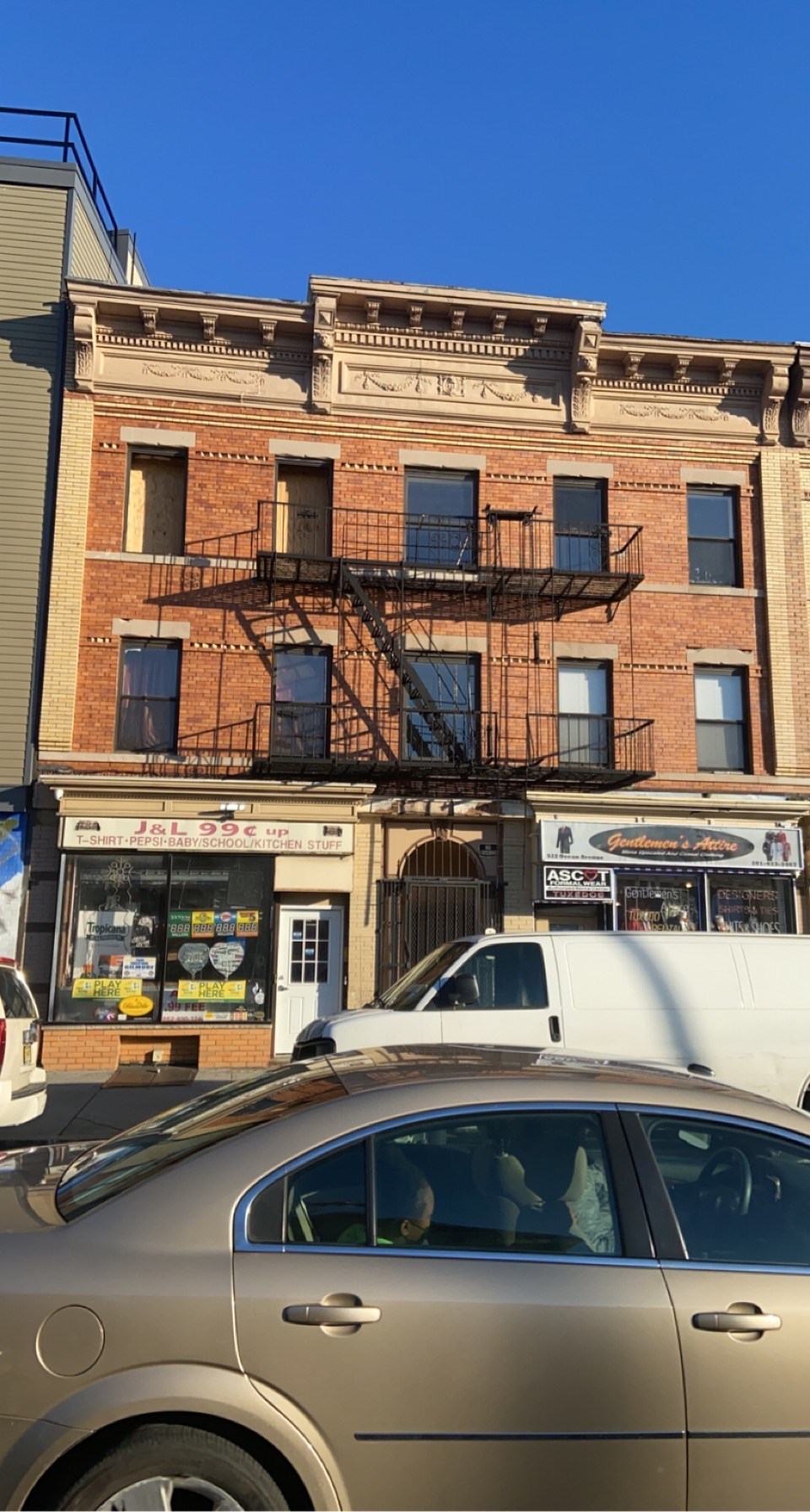 A car is parked in front of a building with a sign that reads "JL 999".