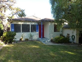 the front of the house with the red door and blue shutters
