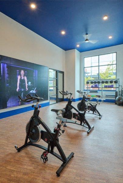 a workout room with exercise bikes and a large screen