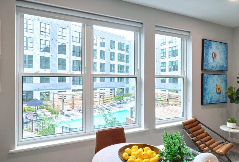 a living room with large windows and a table with a bowl of fruit