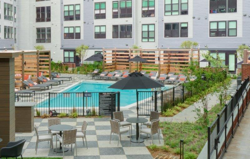 a swimming pool with tables and chairs in front of a building