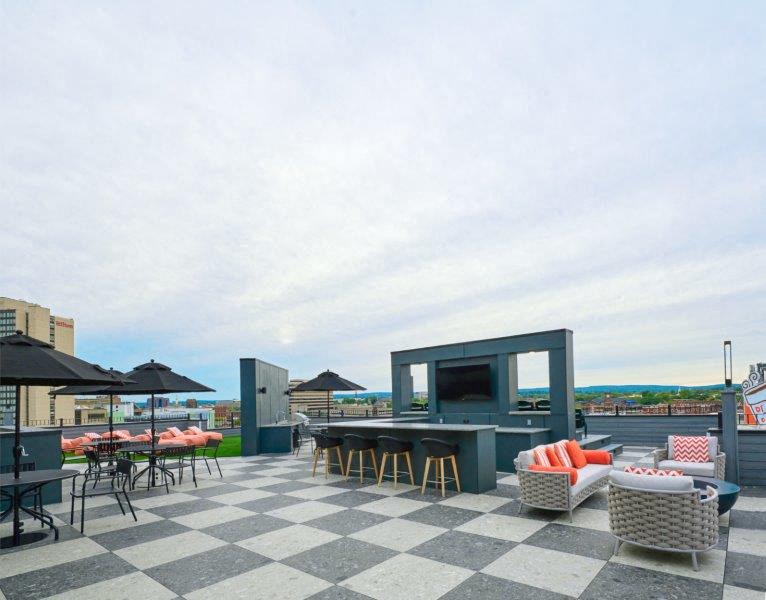 a rooftop patio with tables and chairs and a tv
