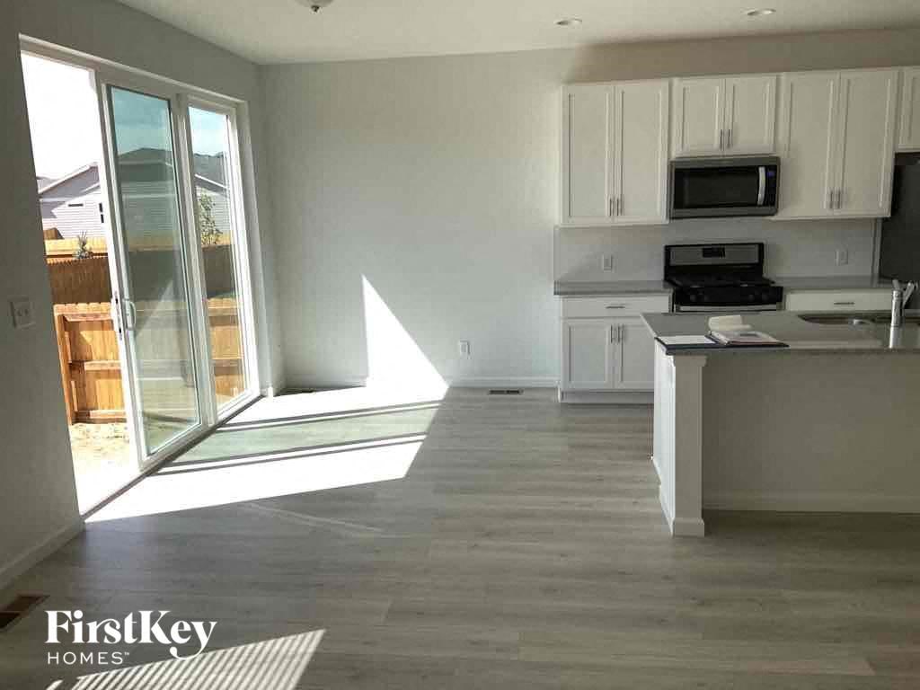 an empty kitchen with white cabinets and a window
