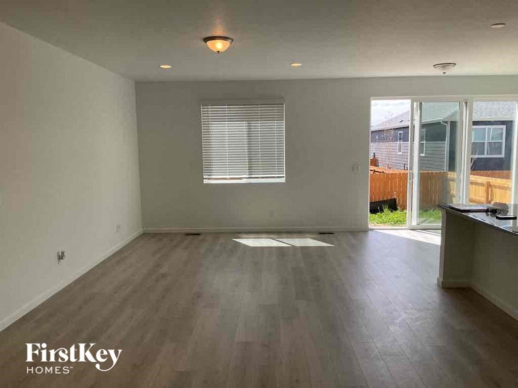 an empty living room with wood flooring and a window