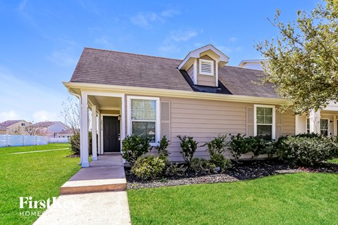 a beige house with a sidewalk in front of it