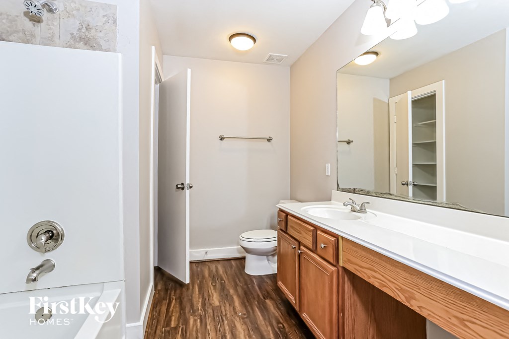 a bathroom with a toilet sink and mirror and a shower