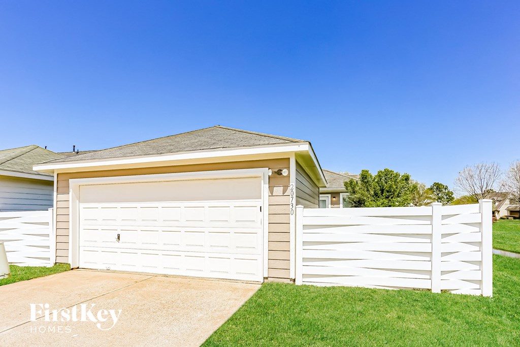 a white garage with a white fence in front of a house