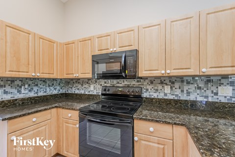 a kitchen with wood cabinets and black appliances and granite counter tops