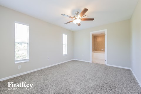 a spacious living room with carpet and a ceiling fan