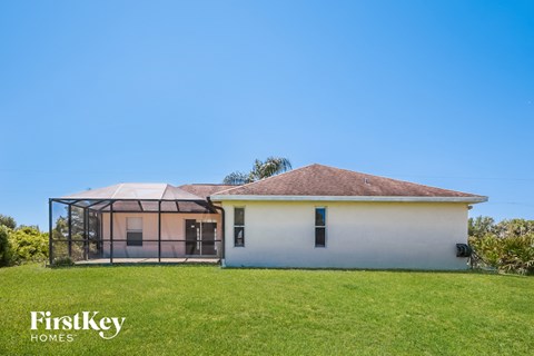a small white house with a greenhouse in a grass field