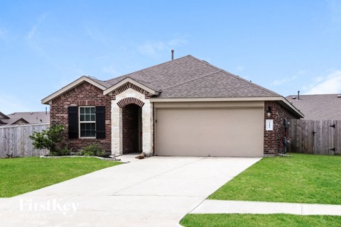 a brick house with a garage door and a lawn