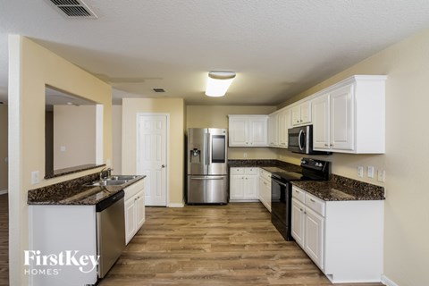 A kitchen with white cabinets and a granite countertop.