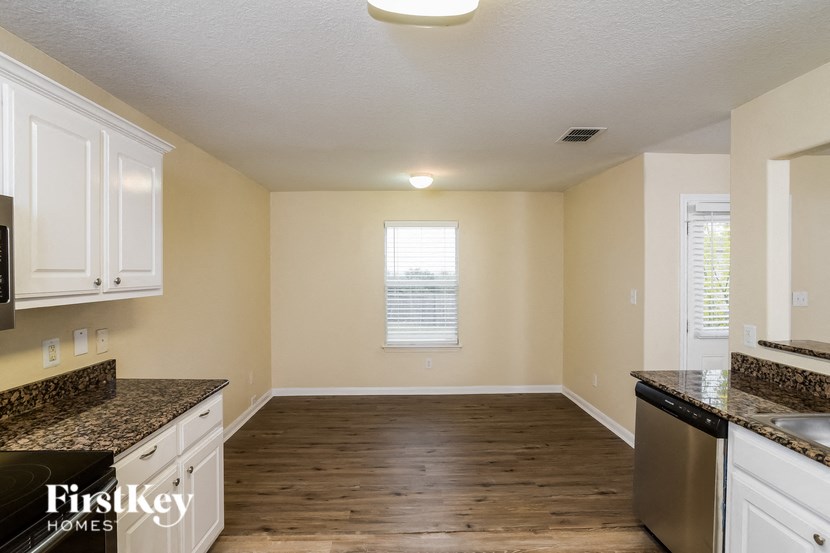 A kitchen with wooden floors and white cabinets.
