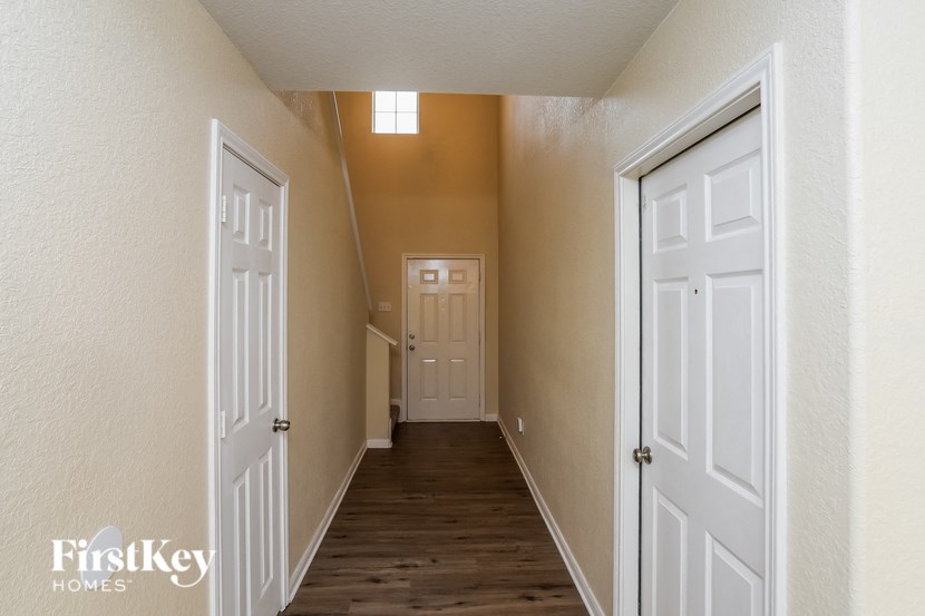 A hallway with two doors on either side leading to a room with a window.