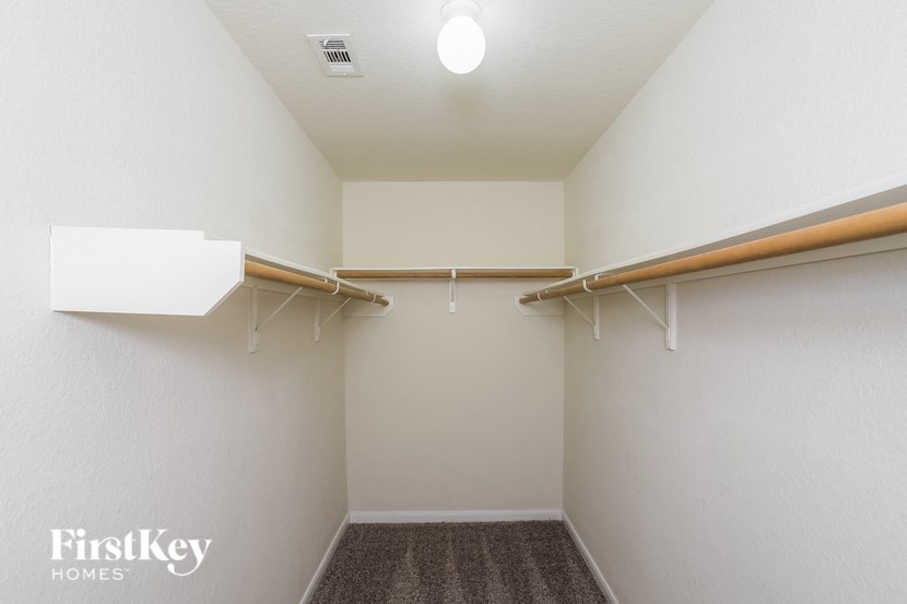 A small, empty closet with a carpeted floor and two wooden hangers.