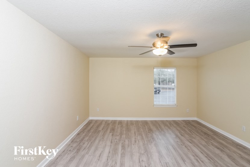 A room with a ceiling fan and wooden flooring.