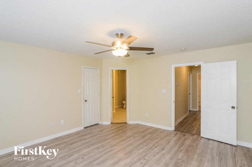 A room with a ceiling fan and wooden flooring.