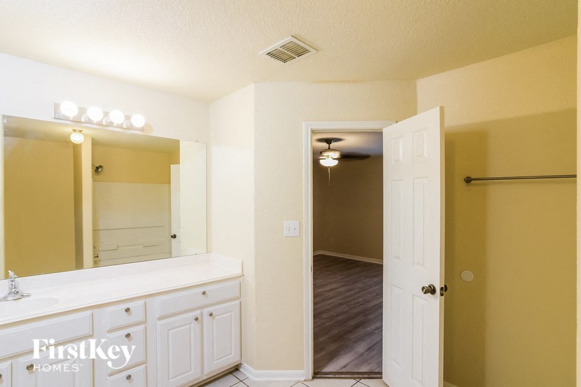 A bathroom with a white vanity and a mirror above it.