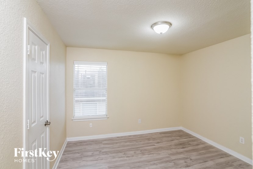 A room with a white door and a window with blinds.