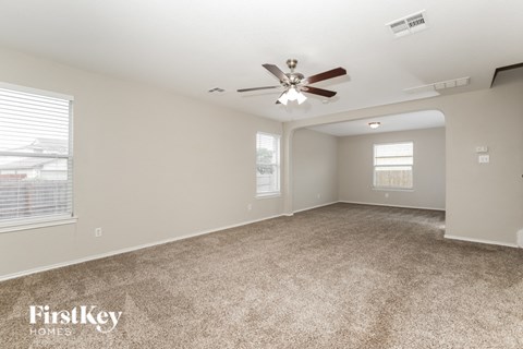 a living room with carpet and a ceiling fan