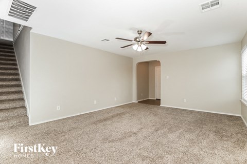 a living room with a ceiling fan and a carpeted floor