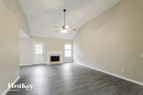 A spacious room with a fireplace and a ceiling fan.
