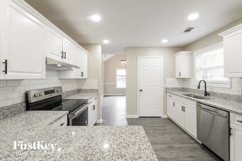 A kitchen with white cabinets and a black stove top oven.