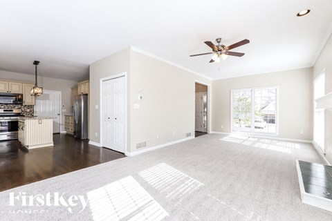A spacious living room with a ceiling fan and a rug on the floor.