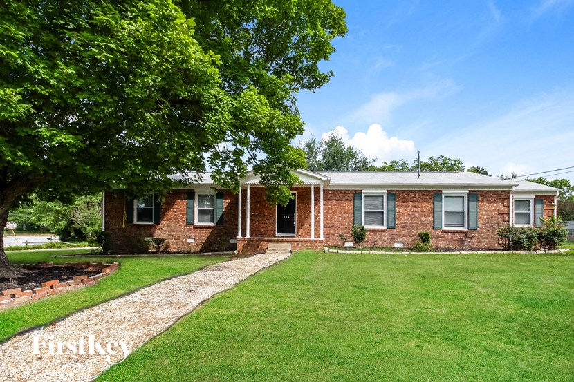 a brick house with a lawn and a tree
