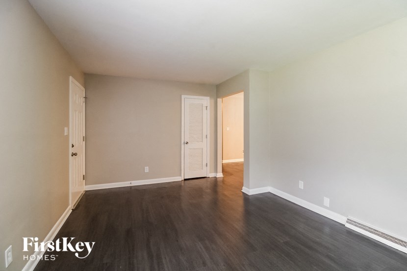 an empty living room with wood floors and white walls