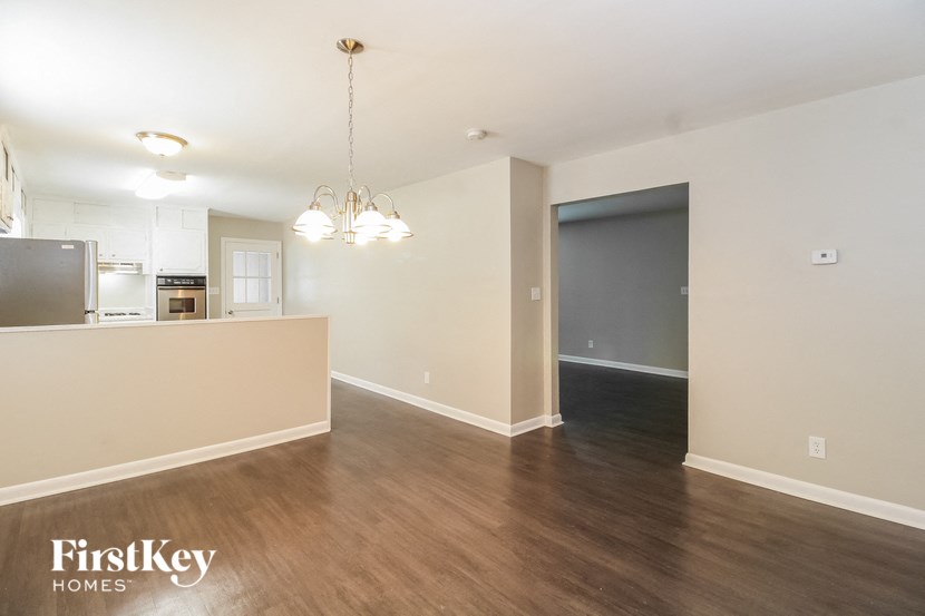 an empty living room and kitchen with wood flooring and white walls