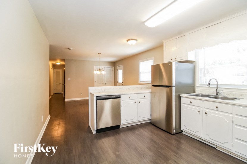 a kitchen with white cabinets and a stainless steel refrigerator and sink