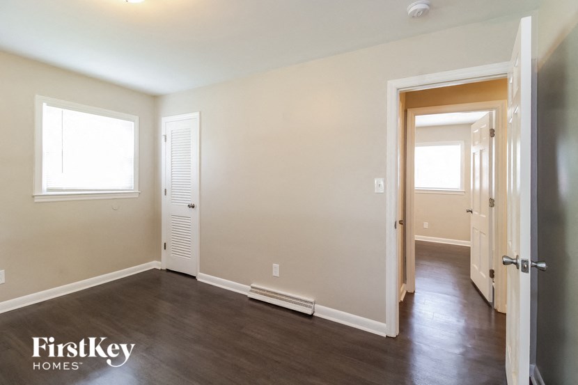 an empty room with hardwood floors and a door to a hallway and a closet