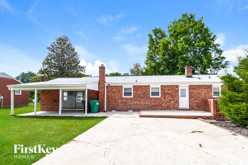 a small brick house with a white roof and a driveway