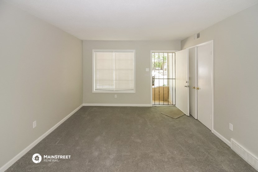 an empty living room with a door and a window