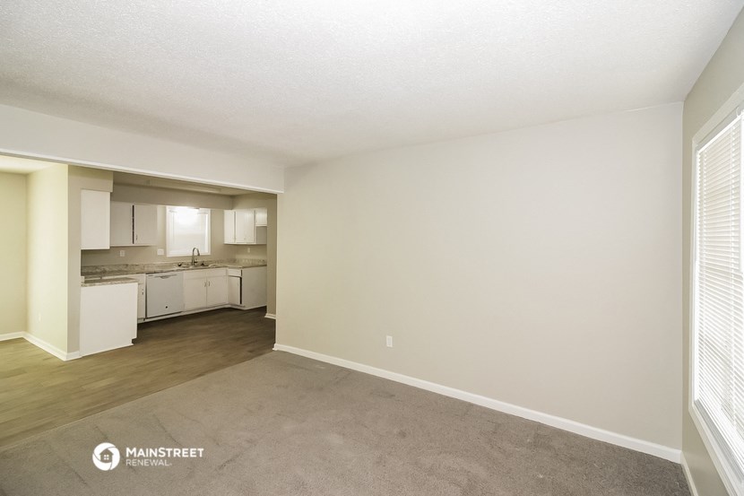 the spacious living room and kitchen of an apartment