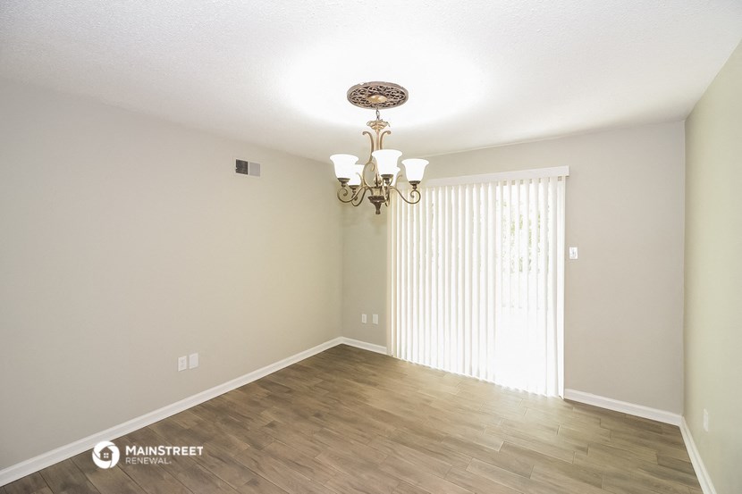 an empty living room with wood flooring and a chandelier