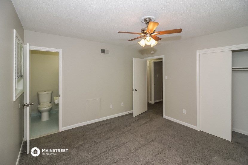 a living room with a ceiling fan and a door to a bathroom