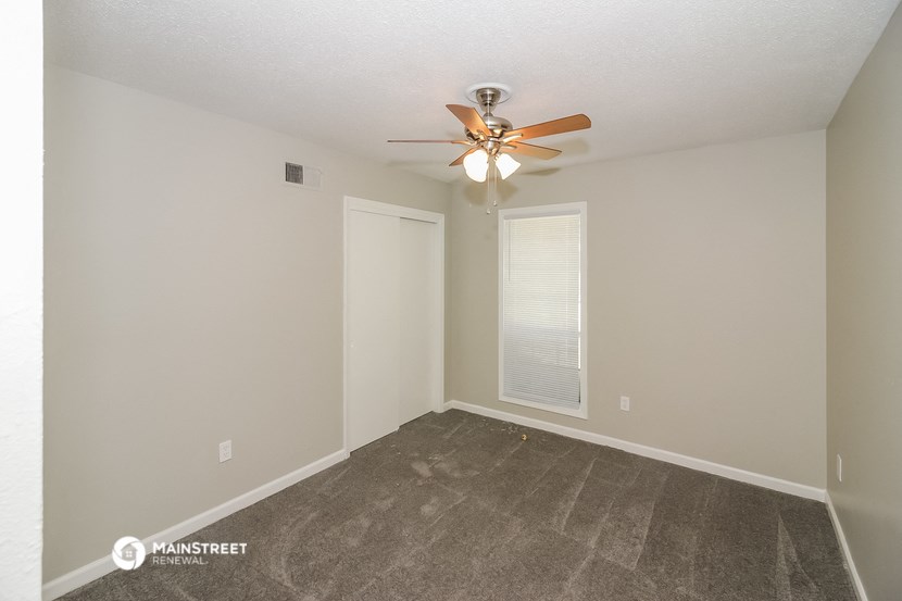 the spacious living room with carpet and a ceiling fan